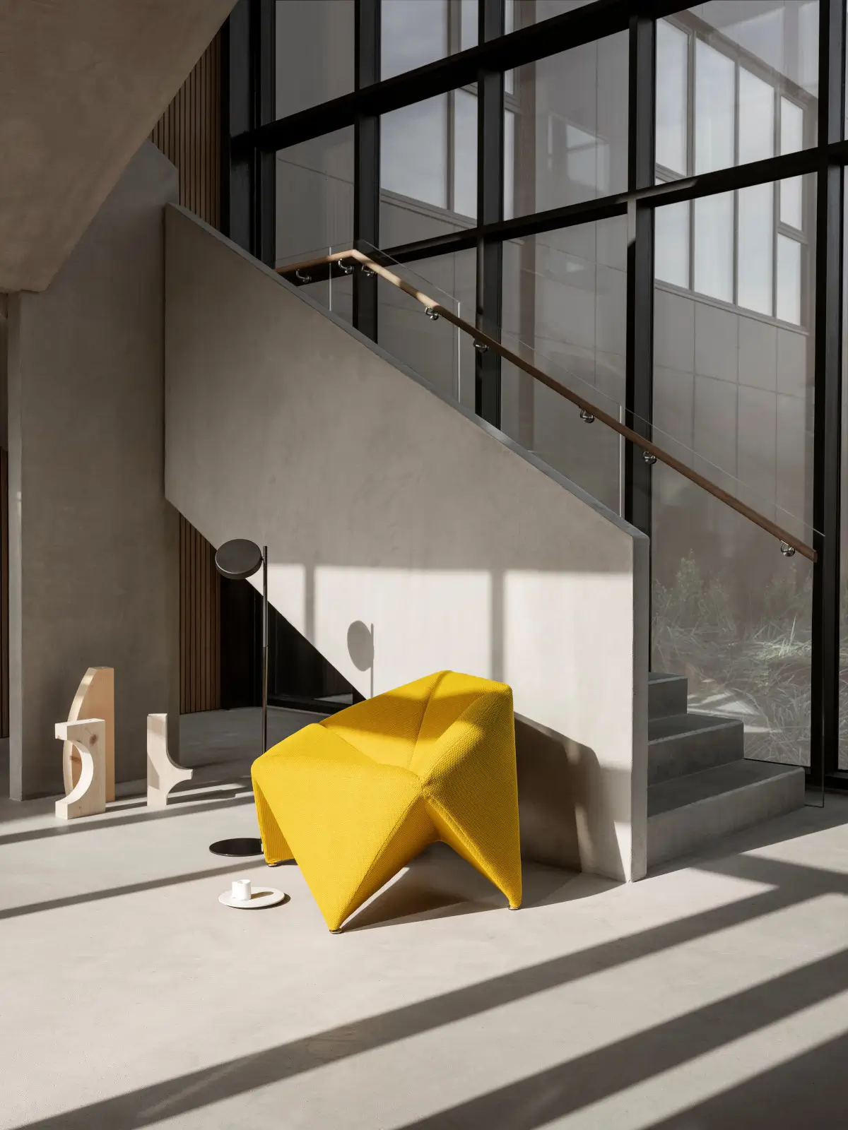 Softline Fold Sessel in Gelb in einem modernen, lichtdurchfluteten Wohnambiente neben einer Treppe mit großen Fensterflächen.