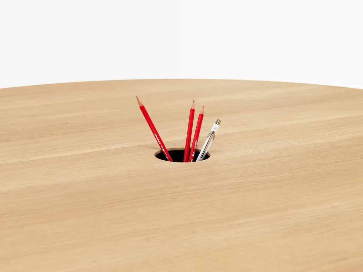 Detailansicht der Holzplatte des Girsberger Tala Rundtischs mit integrierter Öffnung.