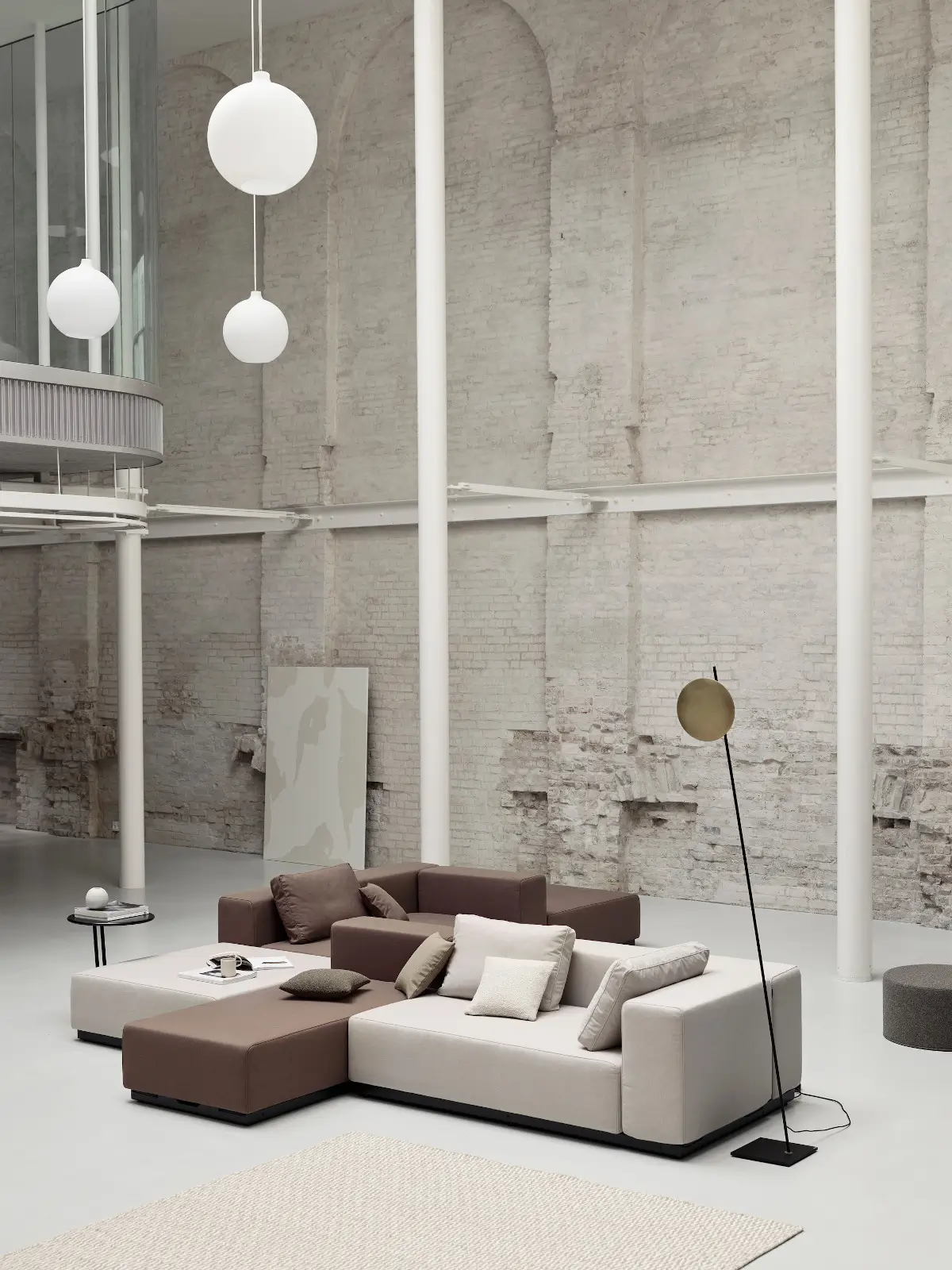 Softline Nevada Sofa 2-Sitzer als Teil einer modularen Sitzlandschaft in Hellgrau und Braun mit Kissen, Teppich und Stehleuchte in großzügigem Lounge-Ambiente.