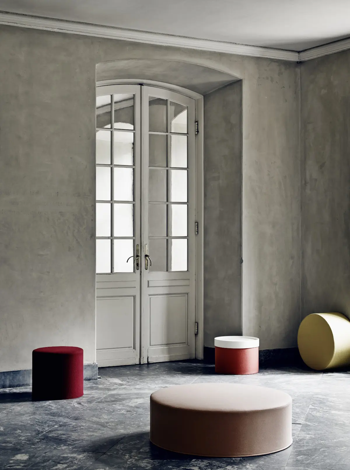Softline Drum Tablett auf einem roten Hocker in einem stilvollen Ambiente mit mehreren runden Softline Hockern in unterschiedlichen Farben und Größen.