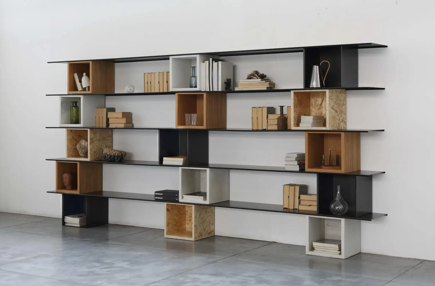 Zeus Ma Dama Bücherregal mit offenen Fächern und modularen Holzelementen in einem modernen Interieur mit dekorativen Wohnaccessoires.