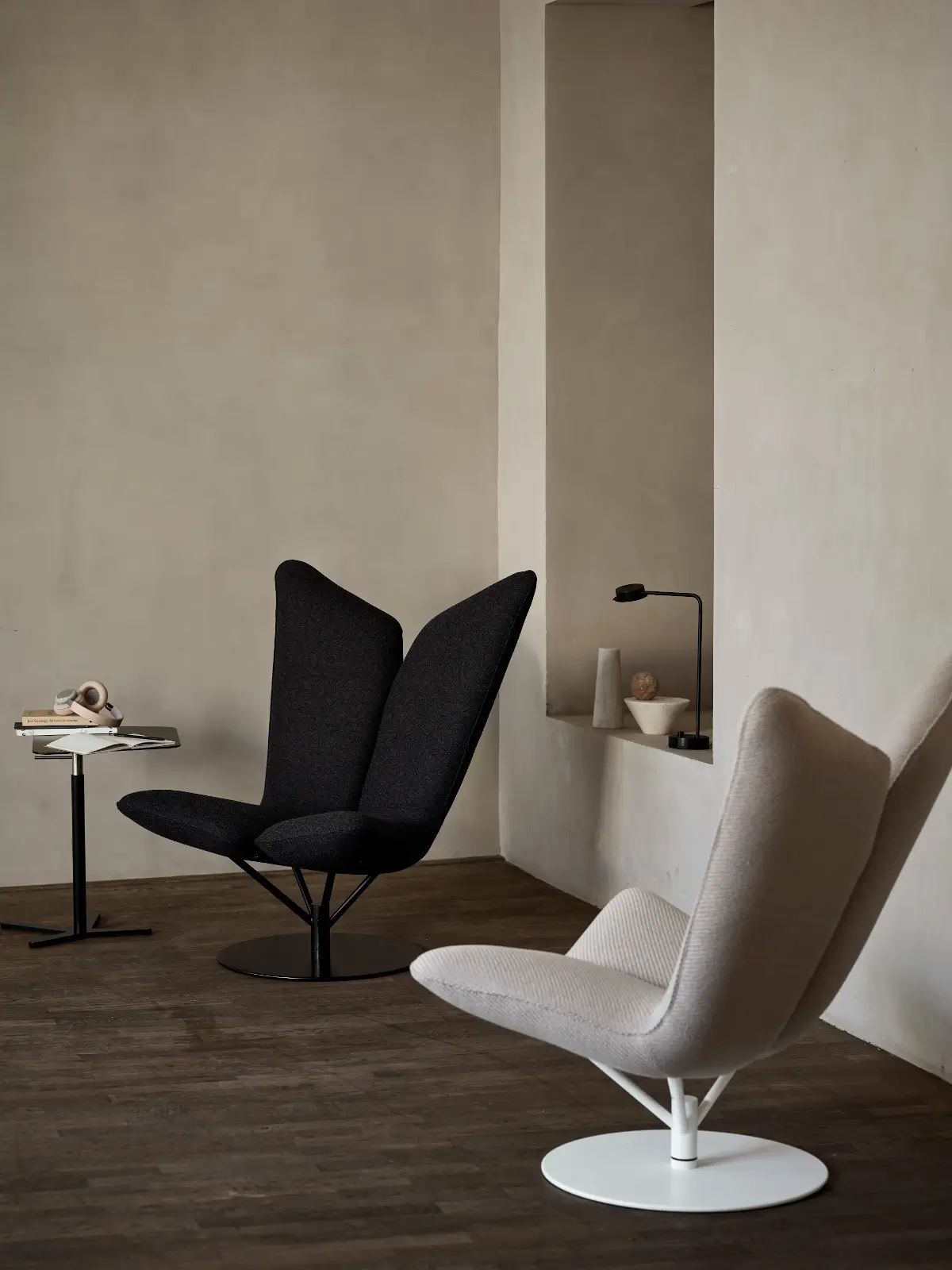 Zwei Softline Angel Drehsessel in Schwarz und Beige mit hohen zweigeteilten Rückenlehnen und Rundfüßen in einem modern eingerichteten Wohnbereich.