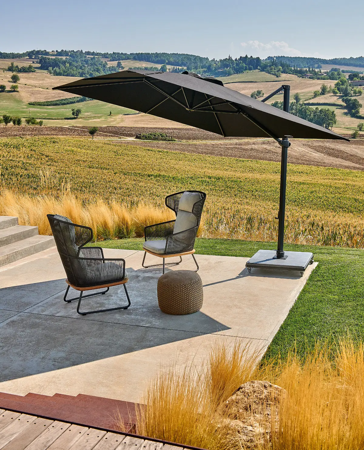 Weishäupl Freiarmschirm auf einer Terrasse mit Sitzgruppe und weitem Landschaftsblick