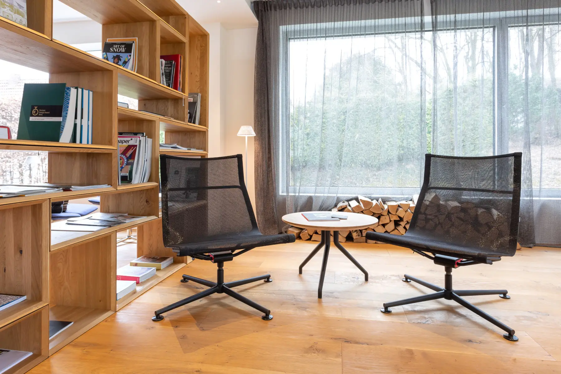 Zwei Wagner d1 Low Lounge Loungesessel in Schwarz mit Beistelltisch in einer stilvollen Lounge mit Bücherregal.