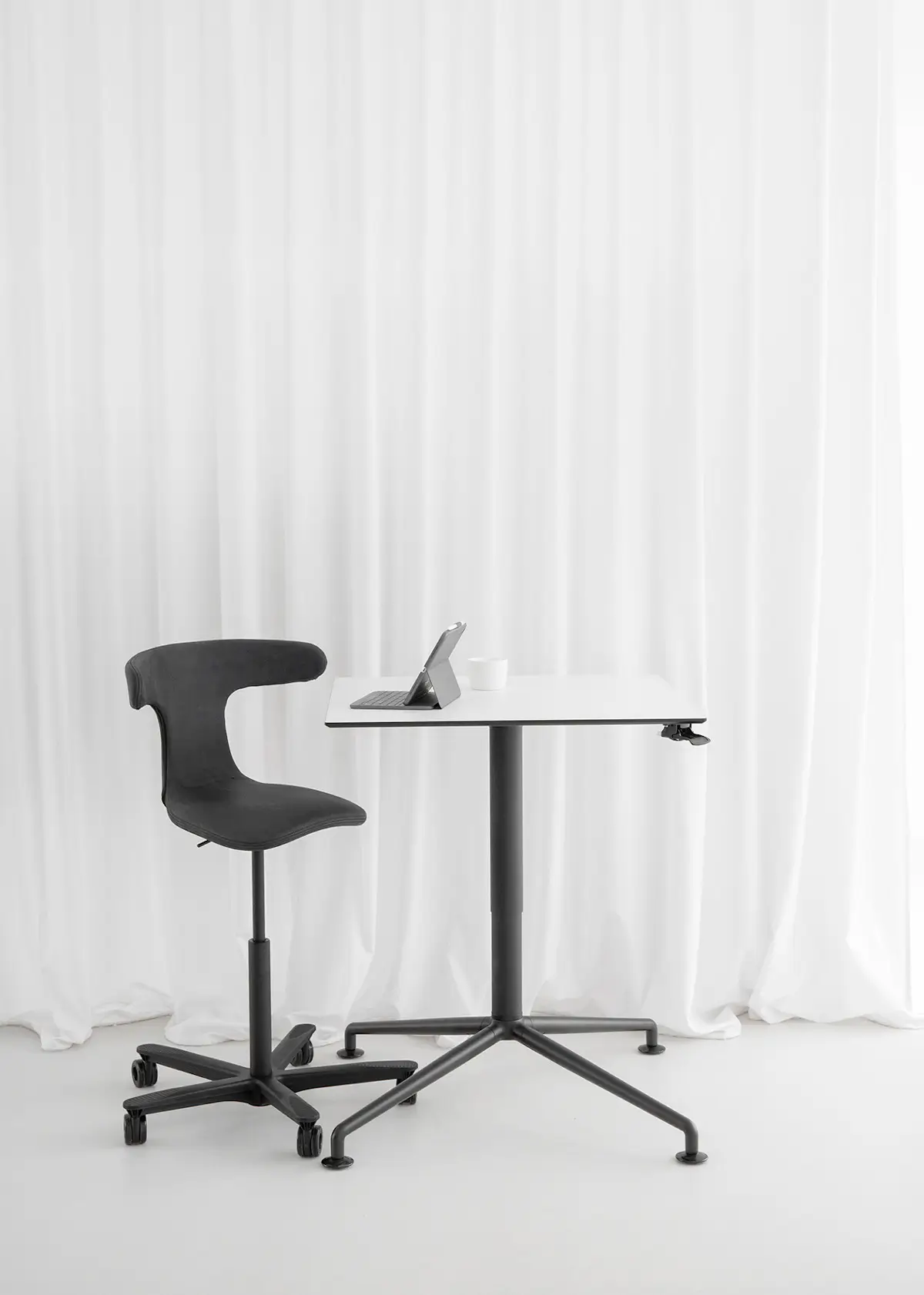 Wagner W-ork Pad Drehstuhl mit schwarzem Stoffbezug an einem Stehtisch im modernen Arbeitsbereich, ideal für aktives Sitzen und flexible Arbeitsplätze.