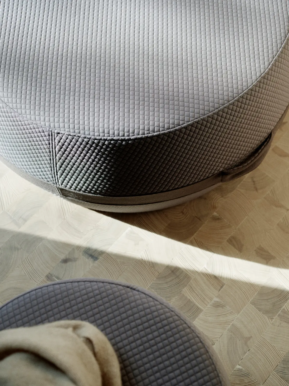 Detailansicht des Softline Lisbon Hockers in Grau mit strukturierter Polsteroberfläche, sichtbarer Naht und umlaufendem Band.