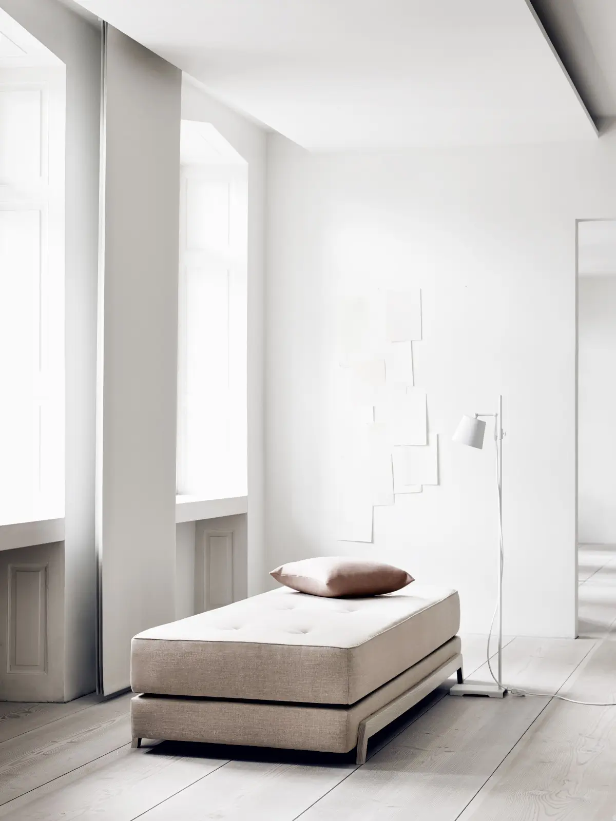 Softline Frame Daybed in Beige in einem hellen minimalistischen Wohnraum mit Kissen, Stehleuchte und Holzboden.