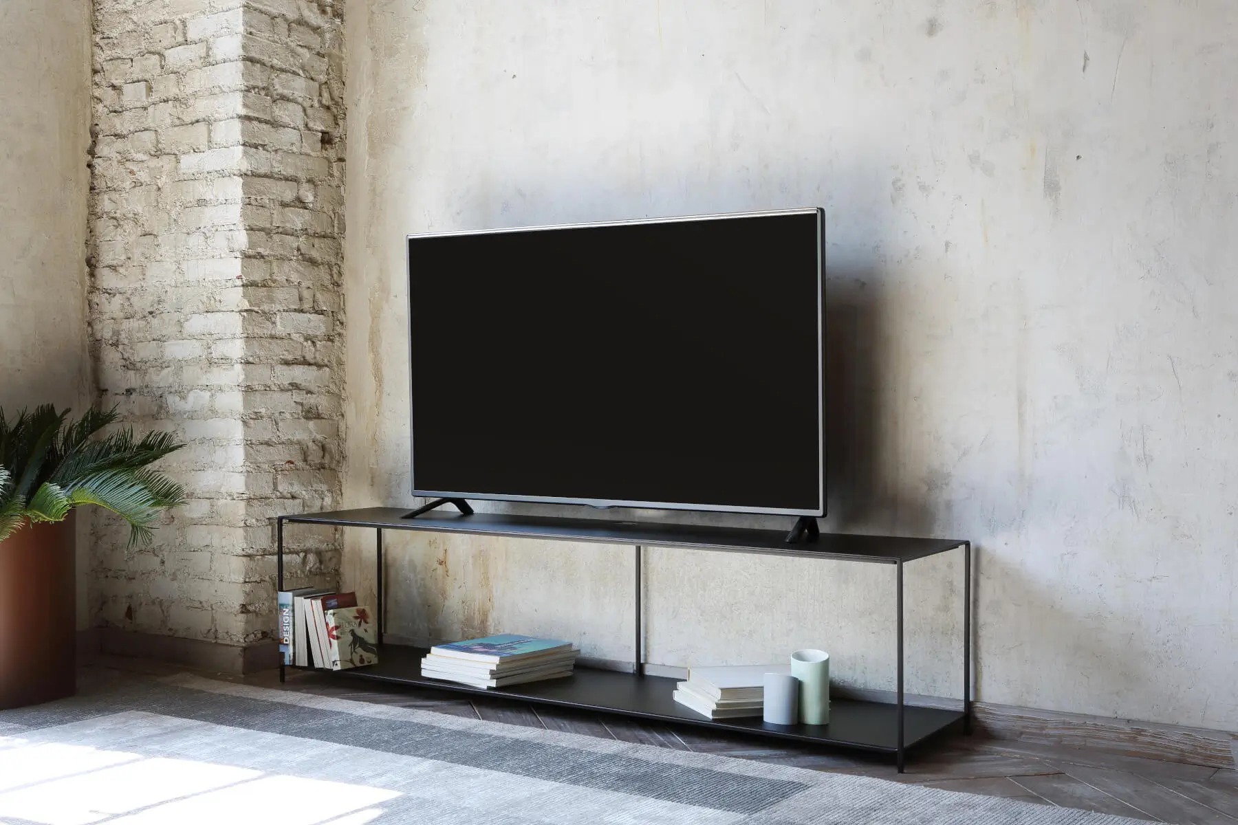 Zeus Slim Irony TV Konsolentisch in einem offenen Loft mit modernem Fernseher und großzügiger Ablagefläche für Bücher und Dekoration.