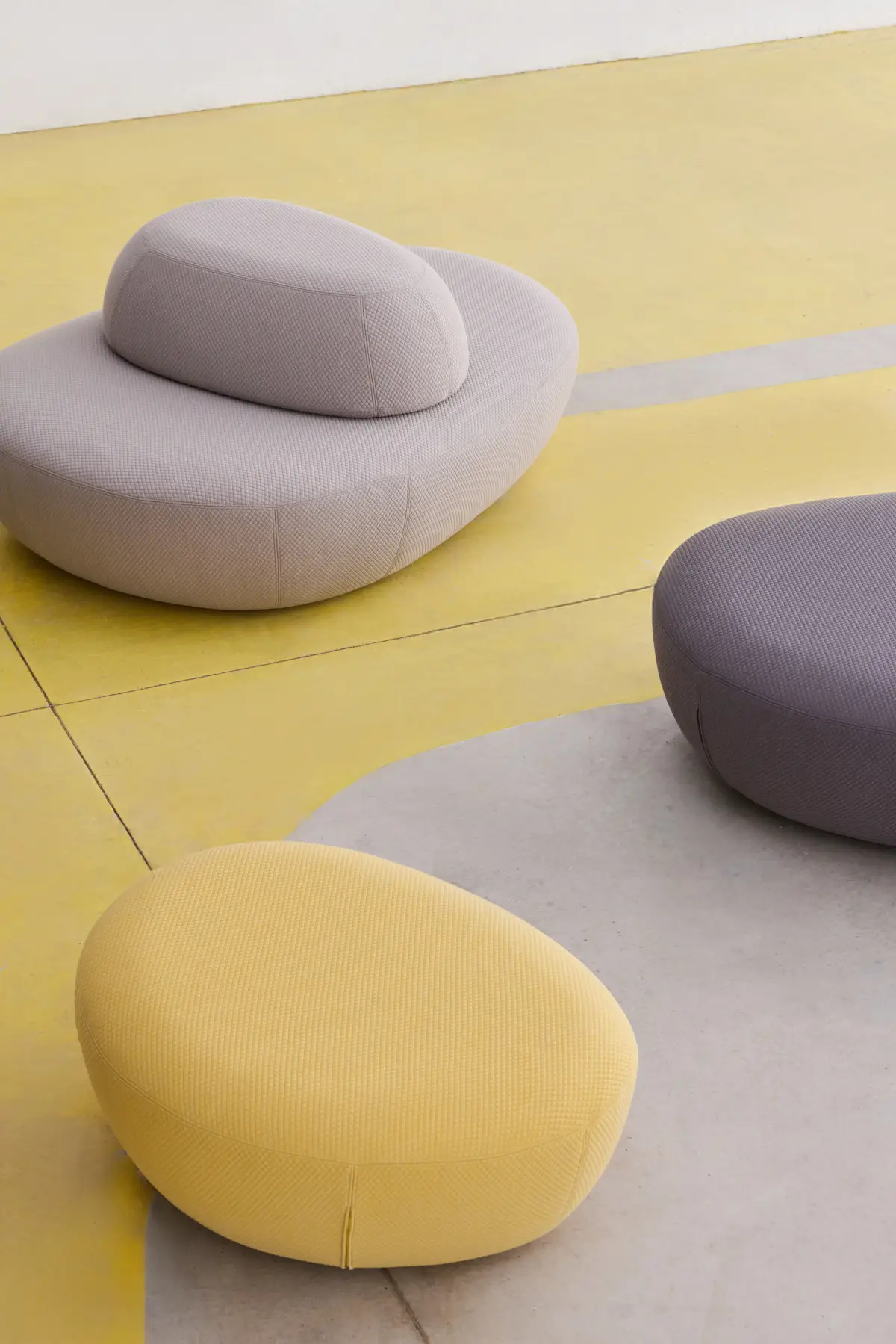 Softline Sisters Hocker Small in Gelb und Grau zusammen mit einem größeren Sisters Sitzelement in hellem Ambiente mit gelbem Boden.