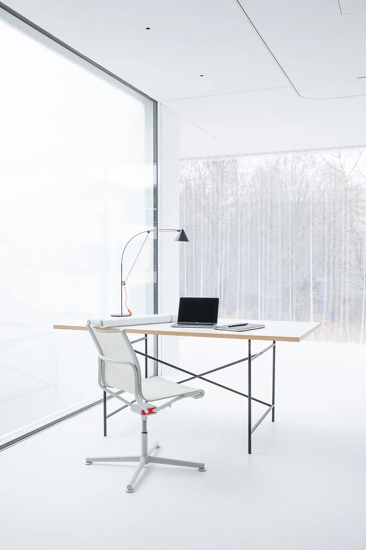 Weißer Wagner d1 Office Besucherstuhl an einem minimalistischen Homeoffice-Schreibtisch mit Laptop und Designleuchte.