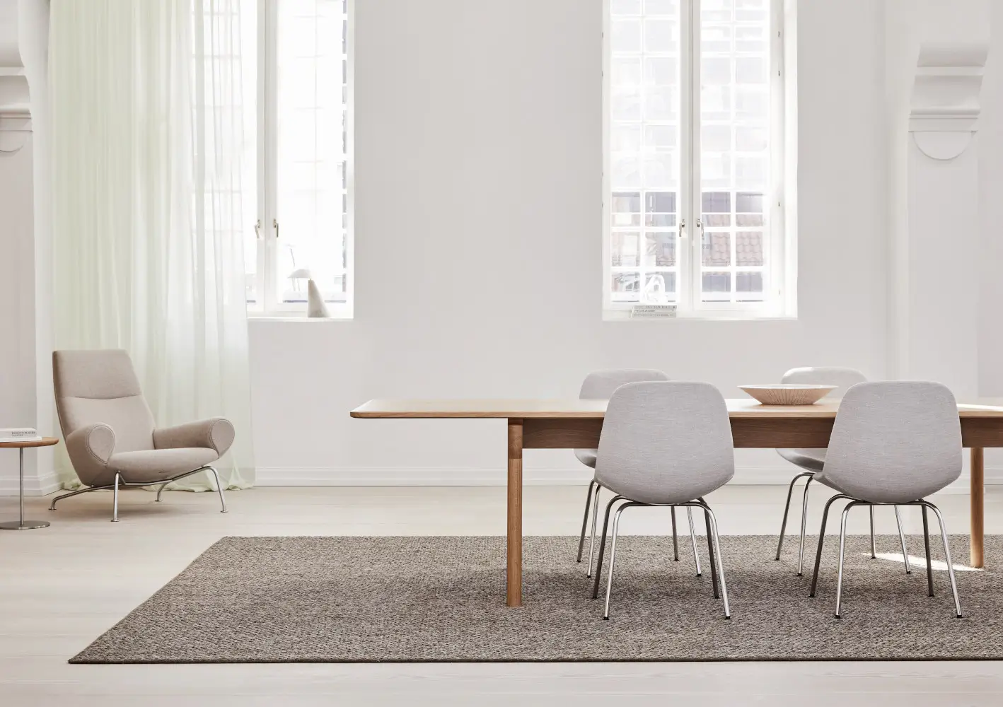 Massimo Copenhagen Belize Teppich in Taupe als rechteckiger Teppich unter einem Holzesstisch mit hellgrauen Stühlen in einem lichtdurchfluteten Esszimmer.