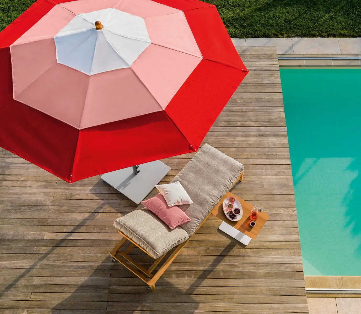 Weishäupl Klassiker Schirm in Kirschrot und Rosa über einer Sonnenliege am Pool