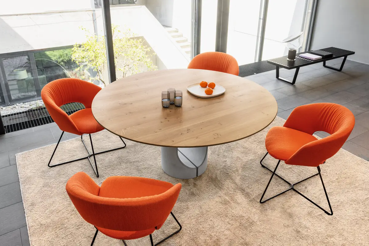 Girsberger Calina Kufenstühle in einer offenen Sitzgruppe rund um einen großen Holztisch für gemeinsame Meetings.