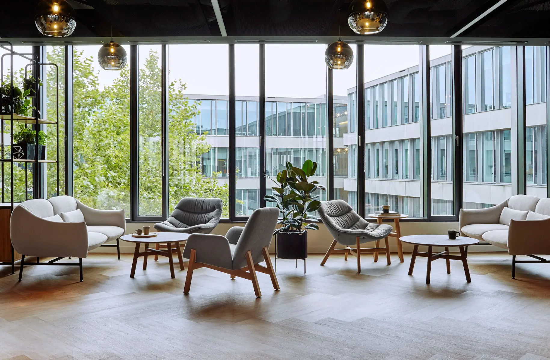 Noti Mishell Couchtisch Ø 80 cm mit Holzbeinen zwischen Sesseln und Sofas in einer modernen Office-Lounge