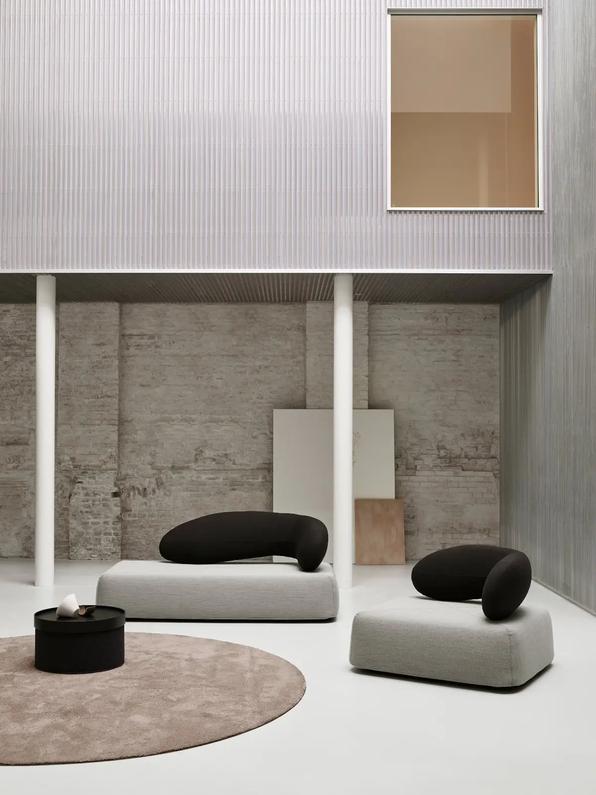 Zwei Softline Chat Sofas in Hellgrau mit schwarzen, organisch geschwungenen Rückenlehnen in einem modernen, offenen Wohnambiente mit rundem Teppich.