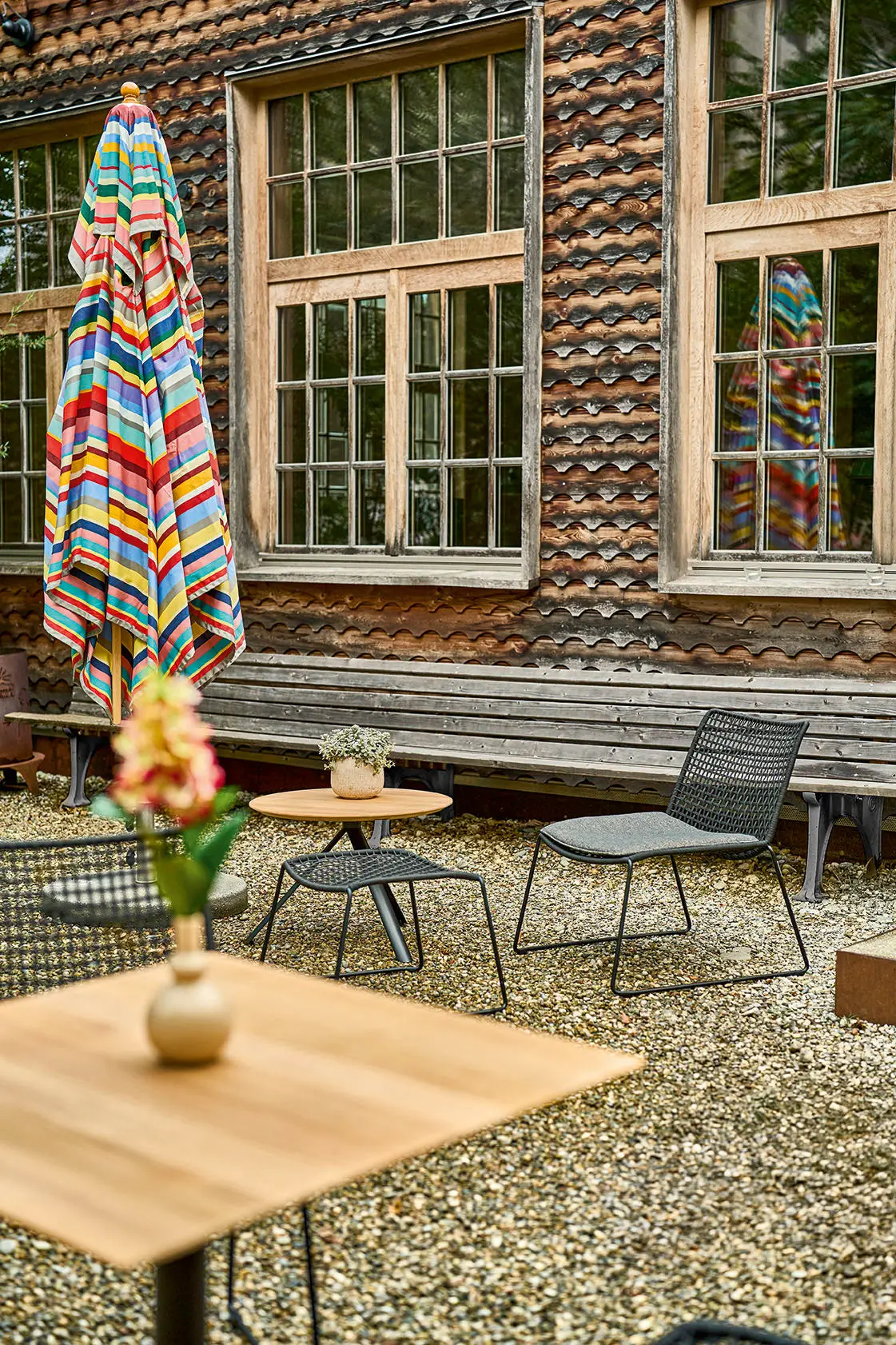 Geschlossener Weishäupl Klassiker Schirm 250 x 250 cm Multicolor vor einer Gartenlounge im Innenhof