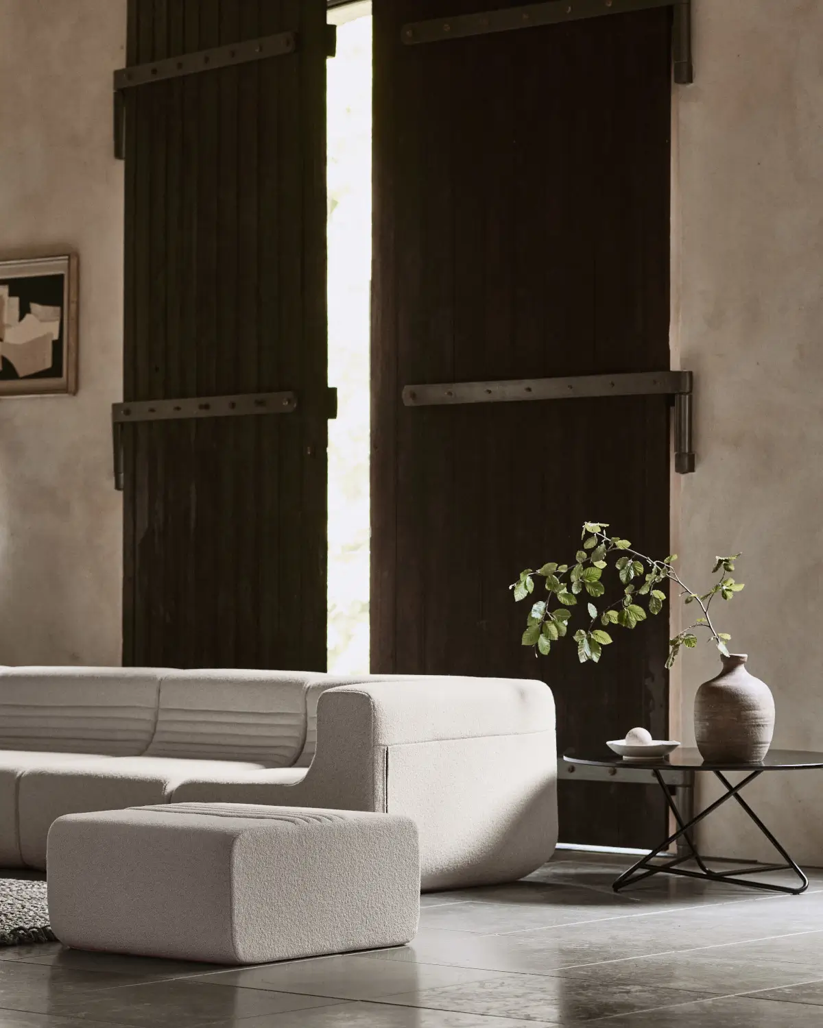 Softline Loft Hocker in Weiß vor einem passenden Sofa in einem stilvollen Wohnambiente mit dunklen Holztüren, Beistelltisch und Vase.