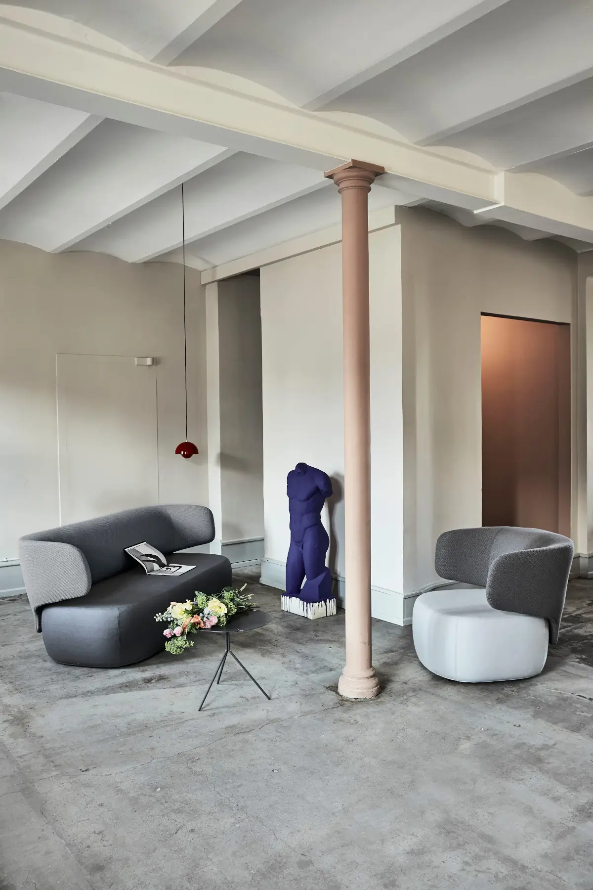 Softline Basel Sessel in Grau in einem modernen Wohnambiente neben einem passenden Sofa, Beistelltisch und dekorativer Skulptur.