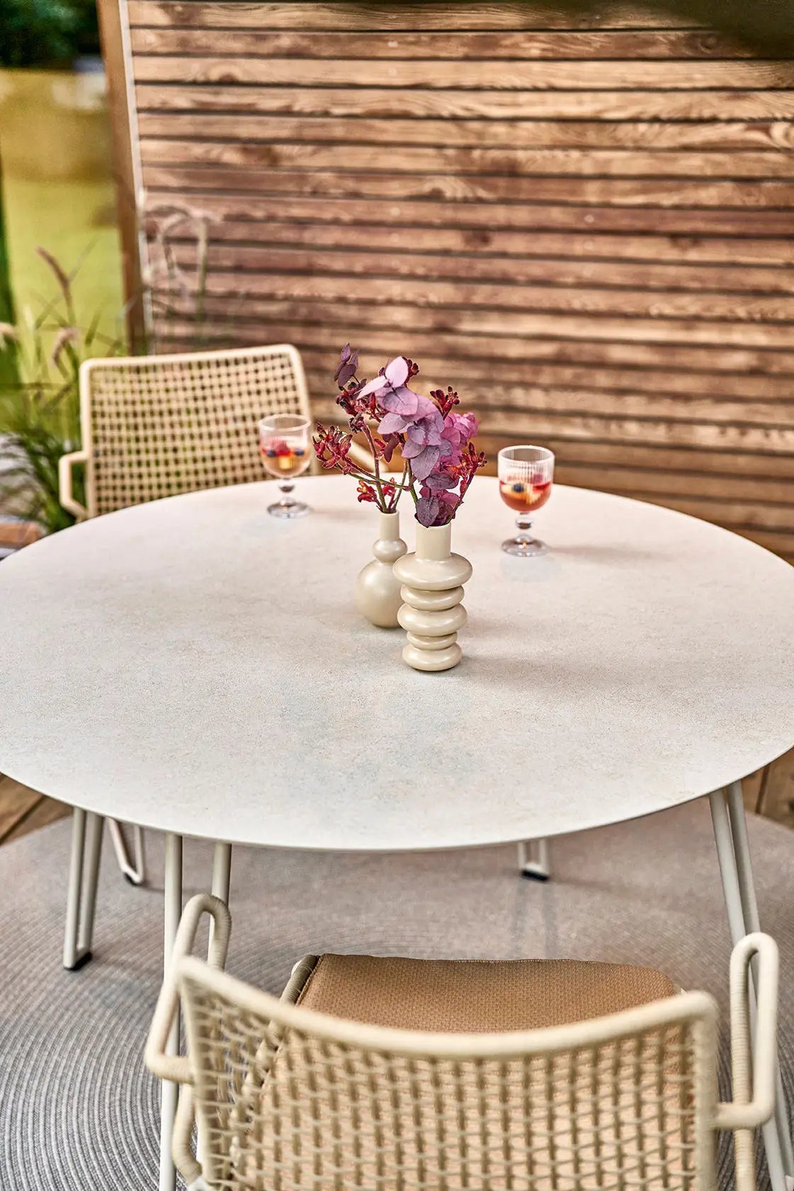 Detailaufnahme des Weishäupl Slope Rundtischs in Perlbeige mit hochwertiger Tischplatte und passenden Gartenstühlen. Elegante Outdoor-Möbel für Terrasse und Garten.