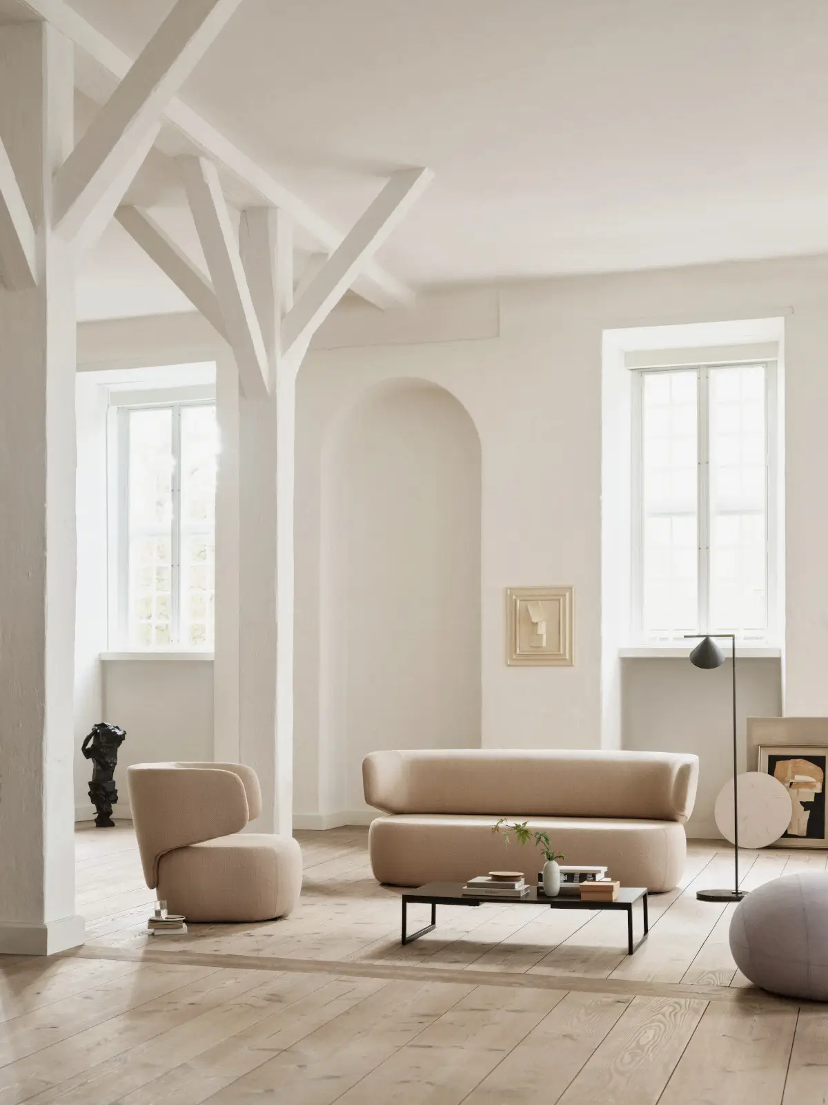 Softline Basel Sofa in Beige mit passendem Basel Sessel in einem hellen Wohnambiente mit Holzboden, Couchtisch und Stehleuchte.