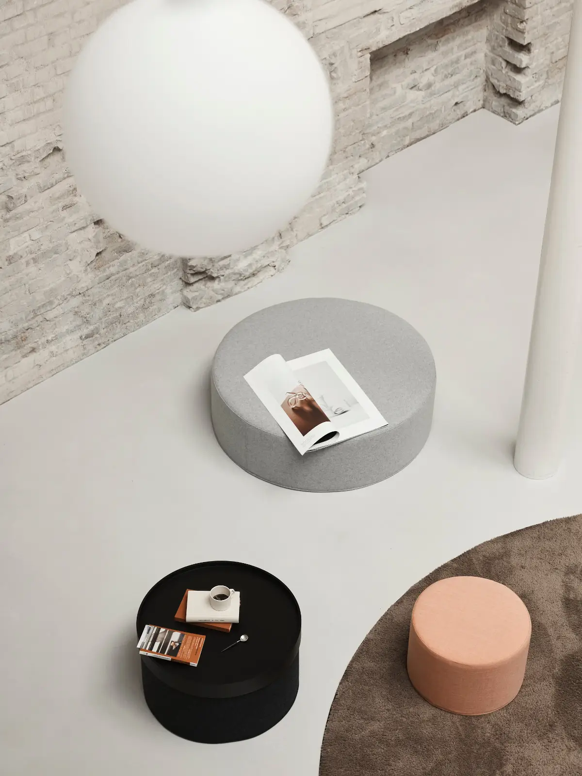 Softline Drum Tablett in Schwarz auf einem runden Hocker, dekoriert mit Tasse und Büchern, in einem modernen Ambiente mit weiteren Hockern in Grau und Apricot.