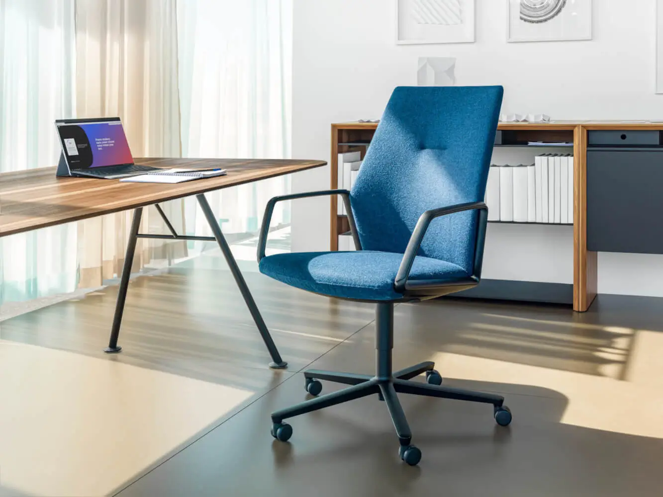Girsberger Eyla Drehstuhl als gepolsterte Sitzlösung an einem Schreibtisch in einem hellen modernen Büro.
