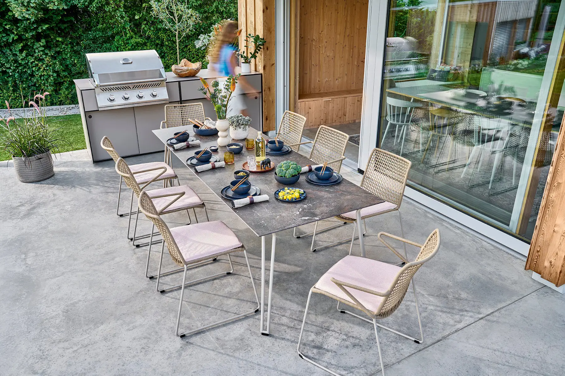 Weishäupl Slope Sitzgruppe mit perlbeigem Gartentisch und Armlehnstühlen auf einer modernen Terrasse. Wetterfeste Outdoor-Designmöbel für Garten und Essbereich.