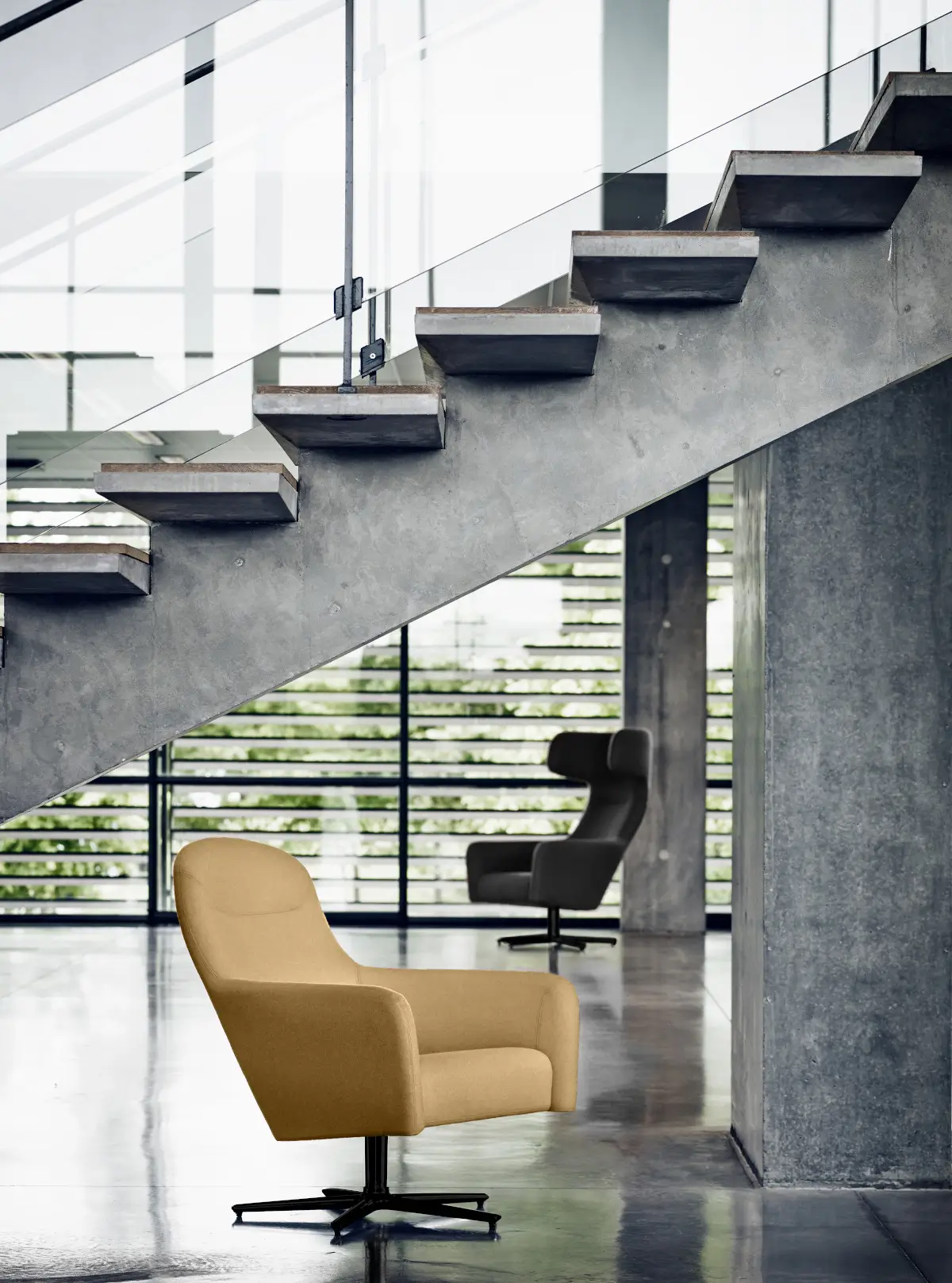 Softline Havana Low Drehsessel in Beige im modernen Ambiente unter einer Betontreppe, mit einem dunklen Havana Hochlehnsessel im Hintergrund.