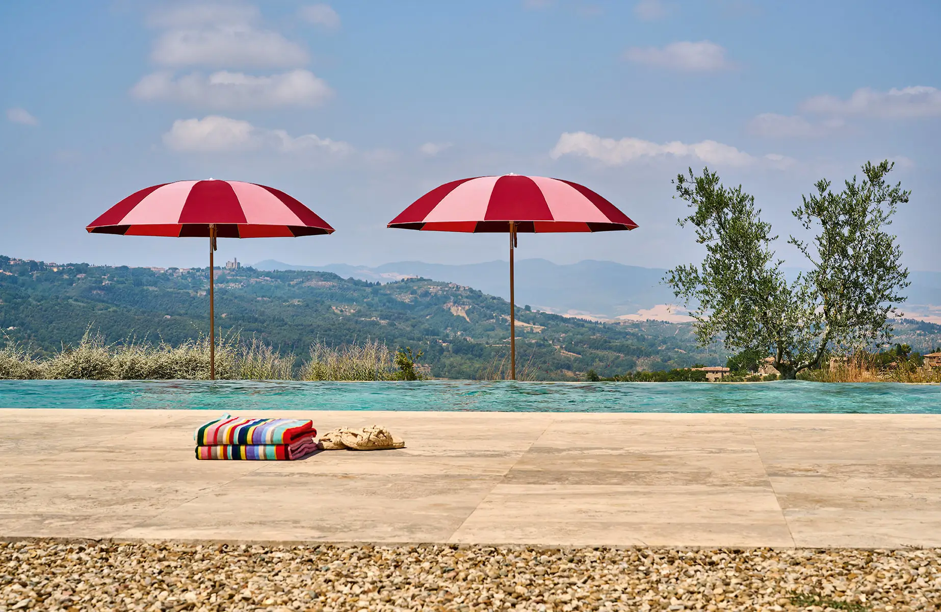 Zwei Weishäupl Pagodenschirme in Rosa und Kirschrot an einem Pool mit Panoramablickv