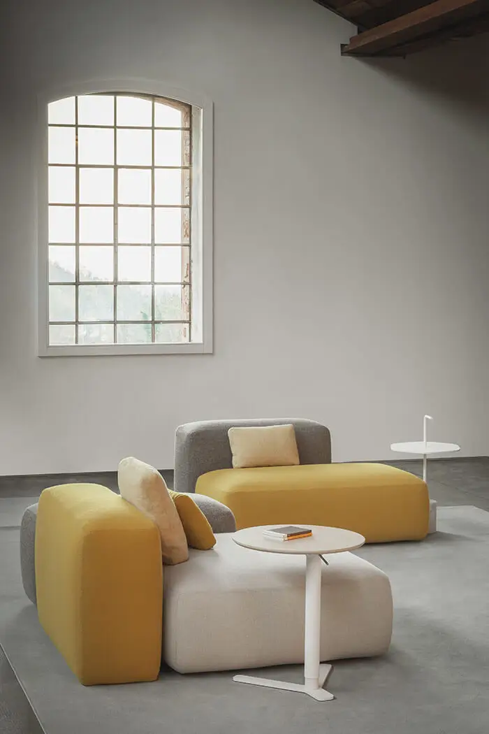 Lapalma YO T80 Beistelltisch als flexible Ablage zwischen modernen Sofamodulen im Wohnzimmer.