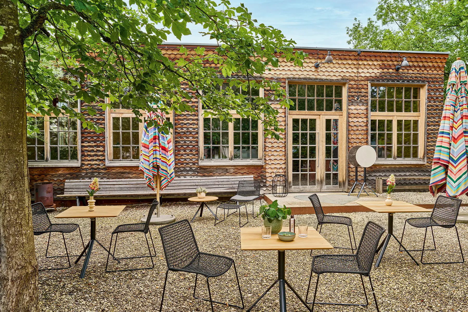 Weishäupl Slope Stühle mit Geflecht an Bistrotischen im Außenbereich – ideal für Café, Restaurant und Terrasse.