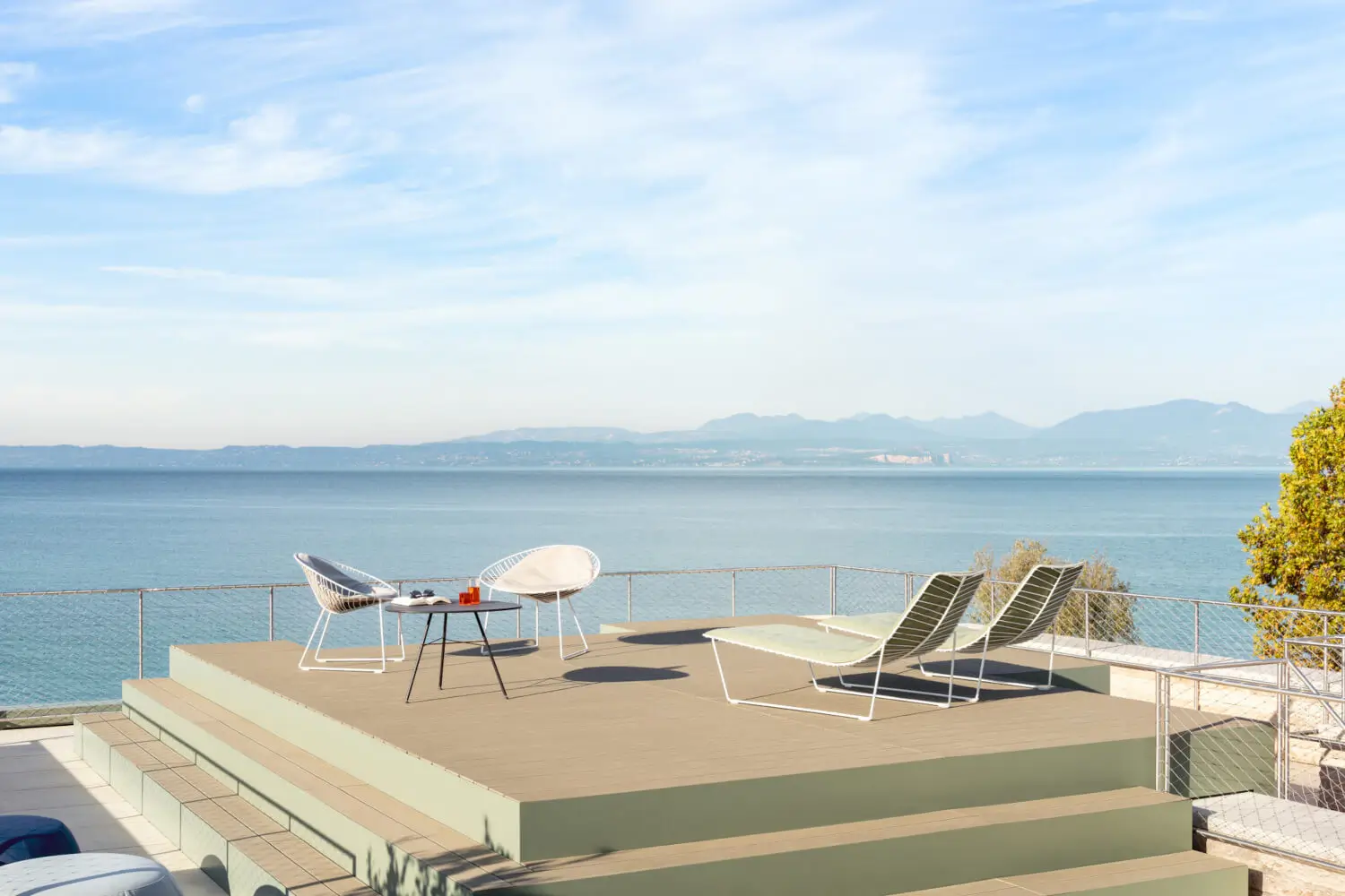 Arper Leaf Beistelltisch mit abgerundeter Tischplatte und filigranem Dreibeingestell auf einer modernen Seeterrasse.