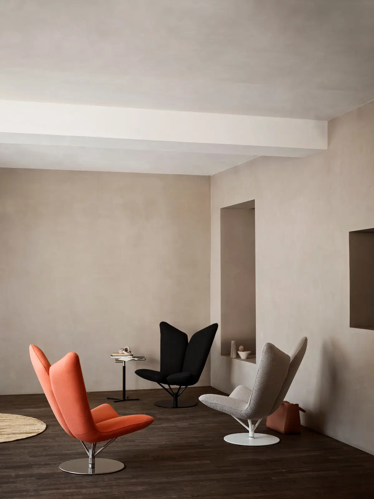 Drei Softline Angel Drehsessel in Orange, Schwarz und Beige mit markanten hohen Rückenlehnen und Rundfüßen in einem modernen Wohnambiente.
