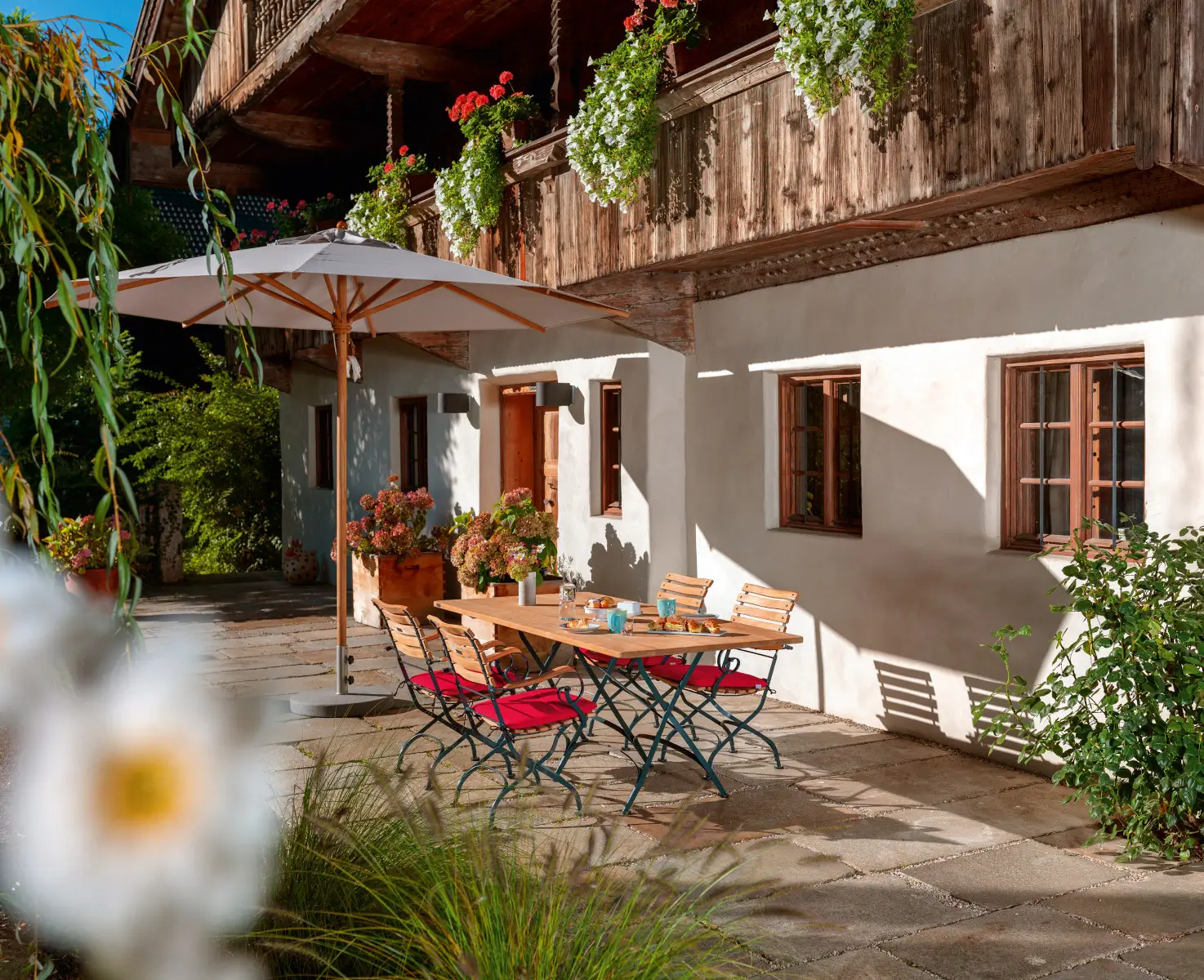 Weishäupl Teakschirm 250 x 250 cm als stilvoller Sonnenschutz über einer Sitzgruppe auf einer mediterranen Terrasse