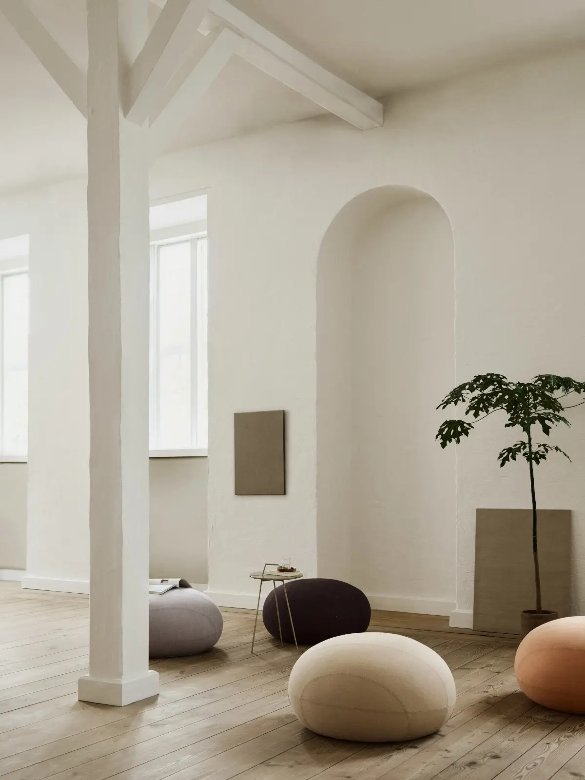 Softline Cut Hocker in Creme, Dunkelbraun, Hellgrau und Orange in einem hellen Wohnraum mit Holzboden, Beistelltisch und Pflanze.