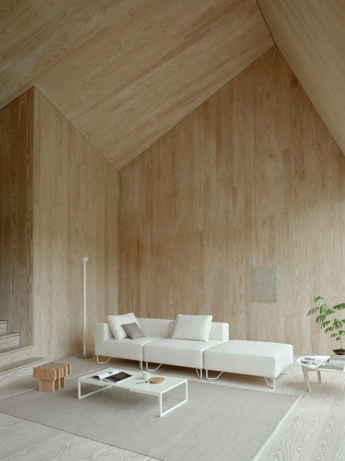 Softline Lotus Sofa in Weiß als modulare Kombination mit großzügiger Liegefläche in einem hellen, vollständig mit Holz gestalteten Wohnambiente.