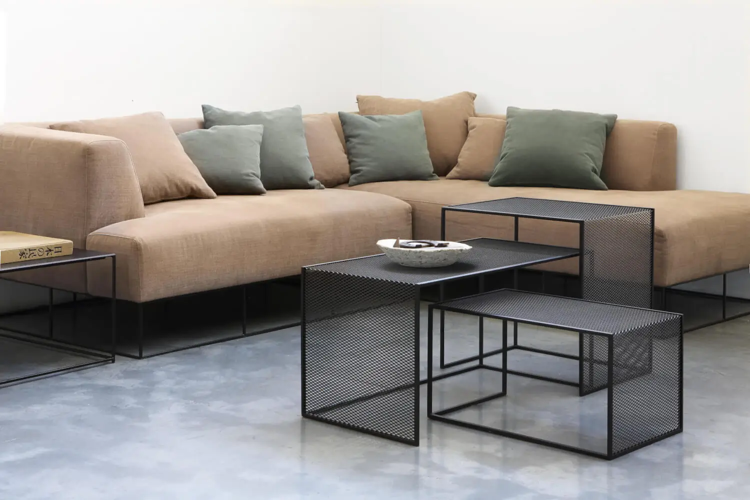 Zeus Tristano Beistelltische aus Streckmetall als moderne Ablage vor einem großzügigen Sofa im Wohnzimmer.