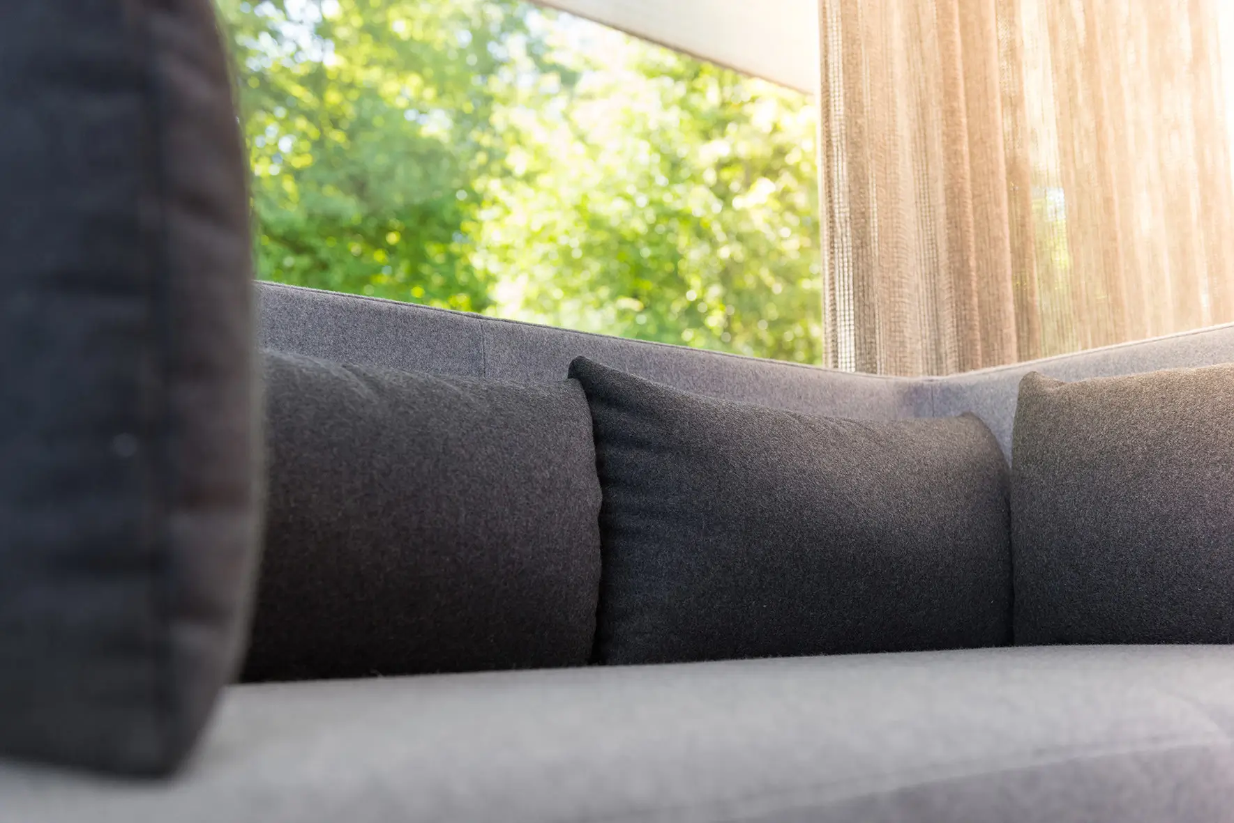 Detailaufnahme des Wagner W-Lounge Low Sofas mit schwarzen Rückenkissen und hellgrauer Polsterung in modernem Wohnambiente.