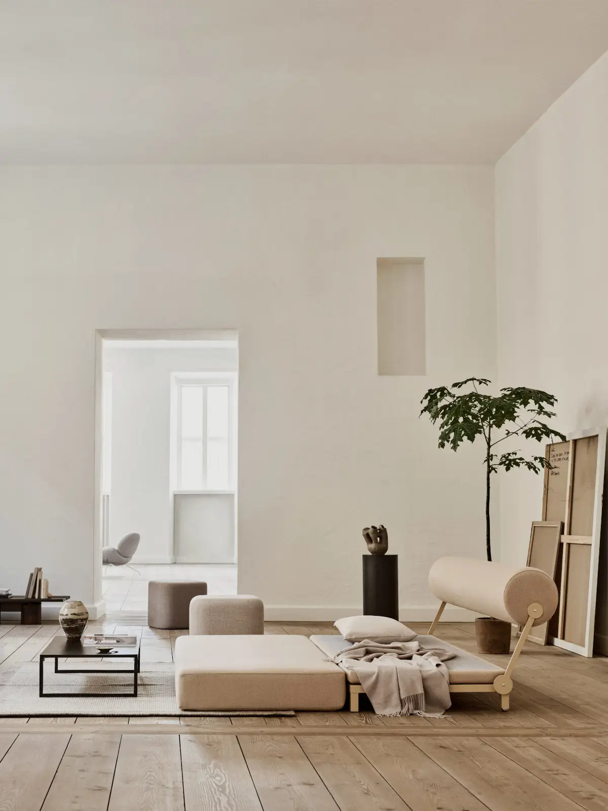Softline Sleep Sofa in Beige als Liegefläche in einem hellen Wohnambiente mit Holzboden, Kissen und zylindrischer Rückenlehne.