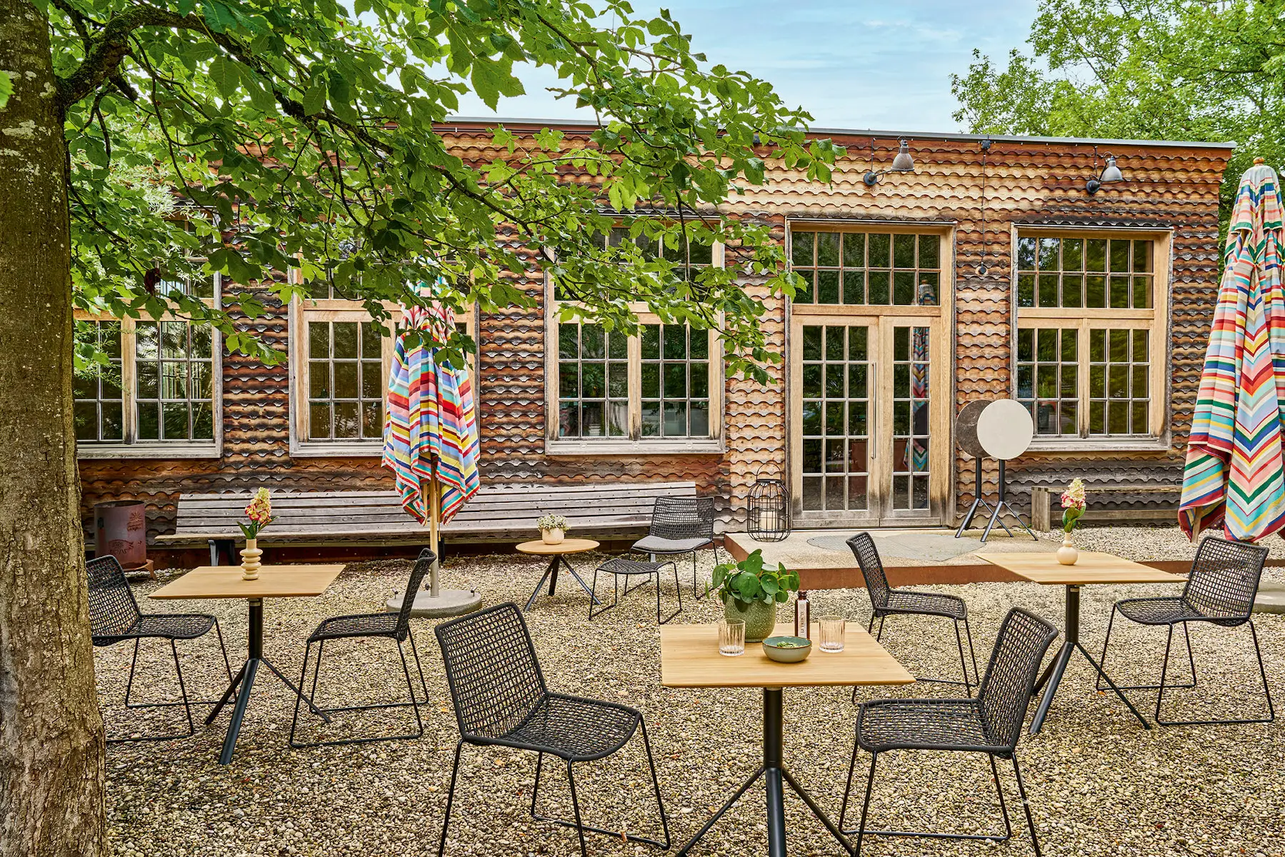 Weishäupl Slope Gartenstühle kombiniert mit Bistrotischen auf einer stilvollen Außenterrasse – wetterfeste Designmöbel für Garten, Terrasse und Gastronomie.