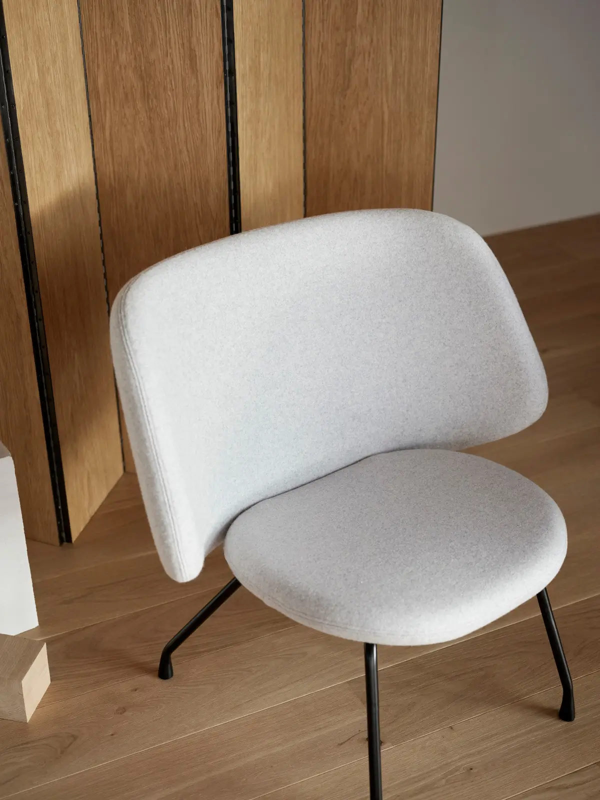 Softline Evy Sessel in Hellgrau im Wohnambiente aus erhöhter Perspektive mit breiter gepolsterter Rückenlehne, Sitzfläche und schwarzem Metallgestell.
