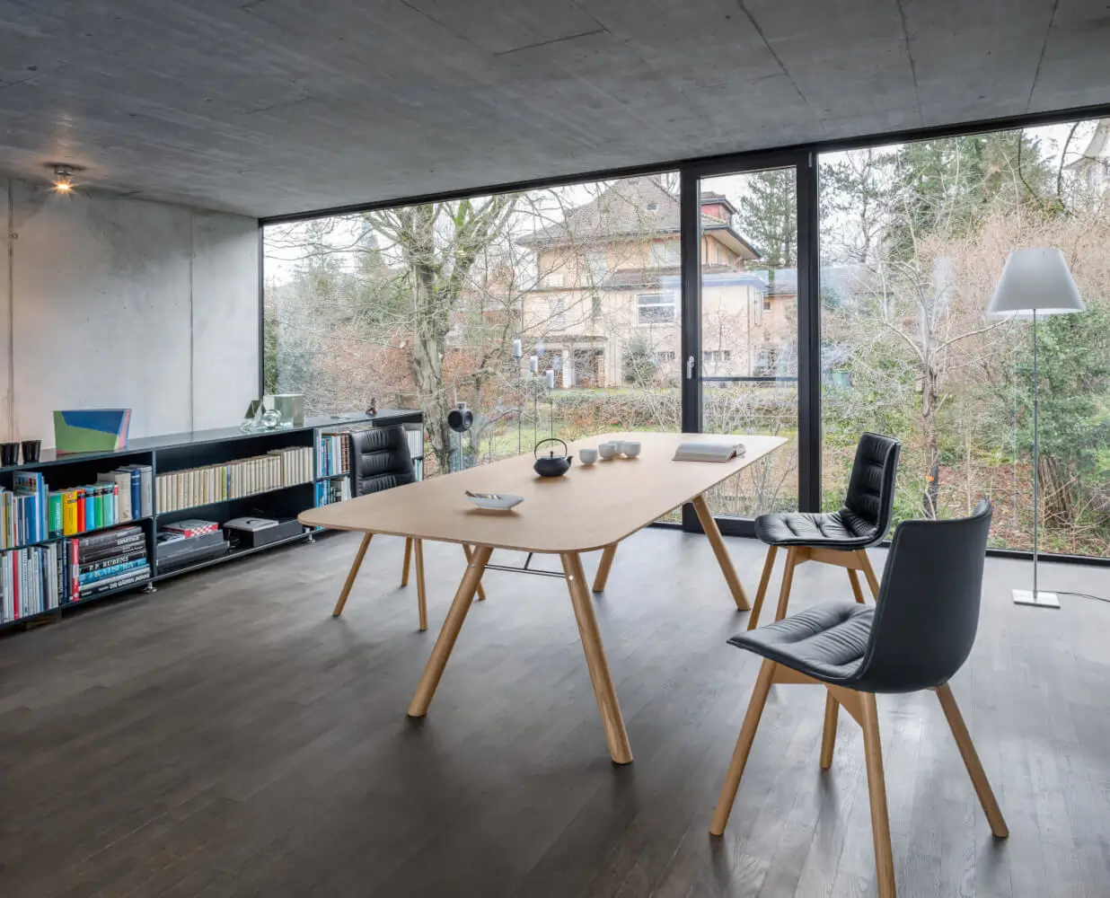 Girsberger Akio Tisch aus Massivholz im modernen Arbeitszimmer mit bodentiefen Fenstern und stilvoller Einrichtung.