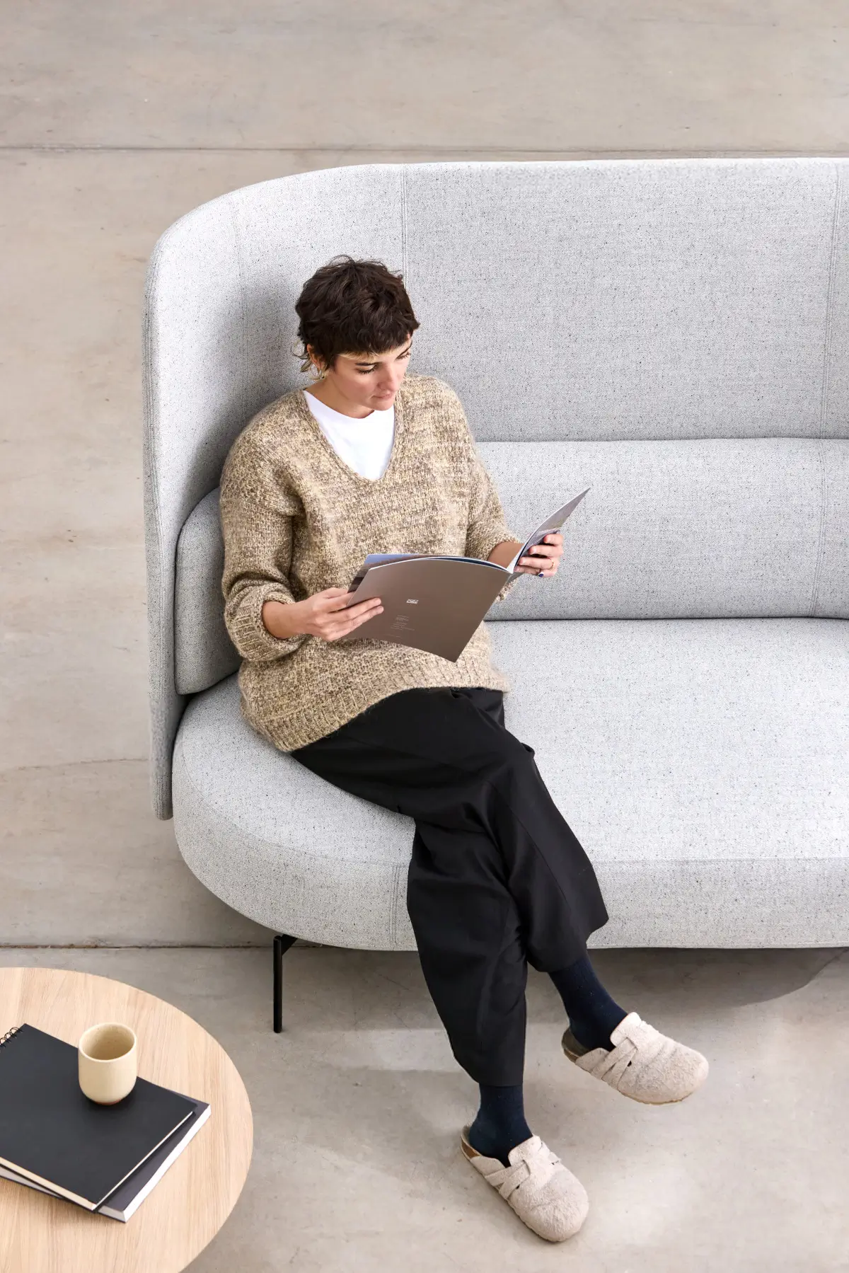 Softline Joe Sofa Hoch in Grau aus erhöhter Perspektive mit hoher gepolsterter Rückenlehne, seitlichen Wangen und einer sitzenden Person.