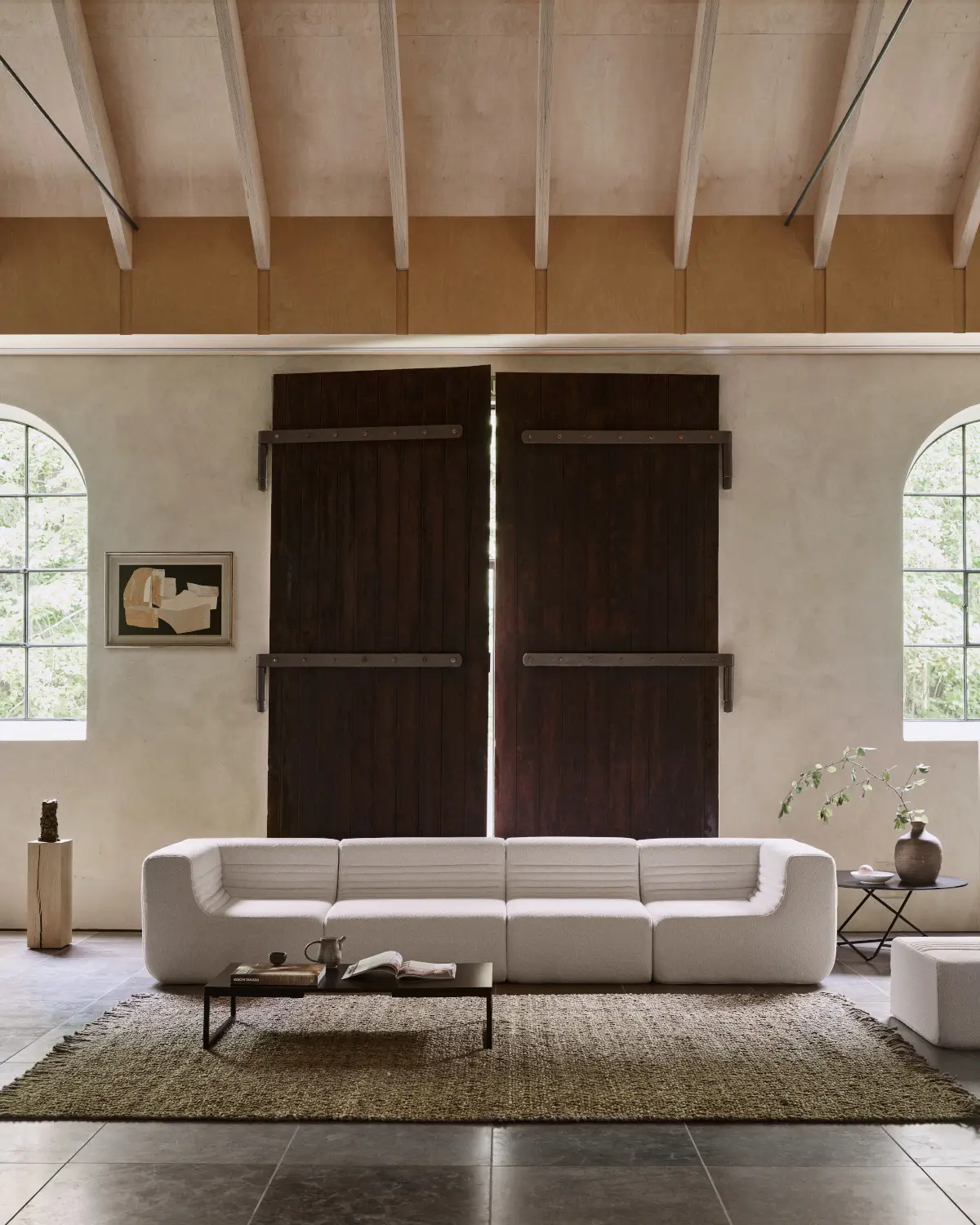 Softline Loft Sofa in Weiß als großzügige modulare Sofalandschaft in einem hellen Wohnambiente mit Teppich, Couchtisch und hohen dunklen Holztüren.