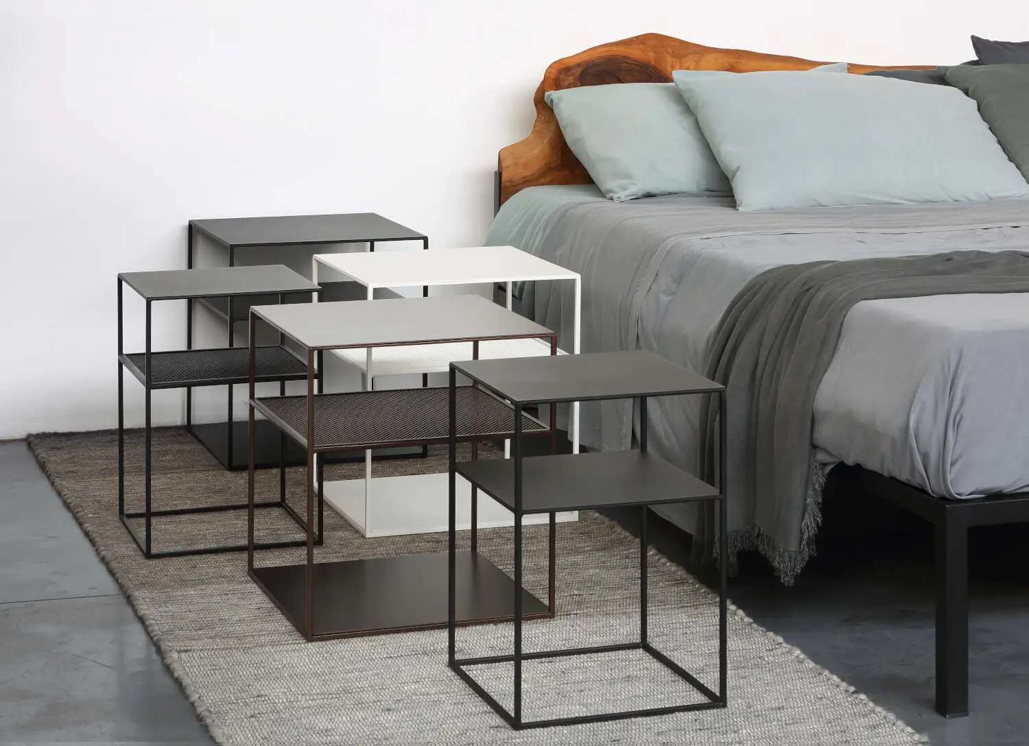 Zeus Slim Irony Triplet Beistelltisch als Nachttisch neben einem Bett mit Holzkopfteil und stilvollen Wohnaccessoires im Schlafzimmer.