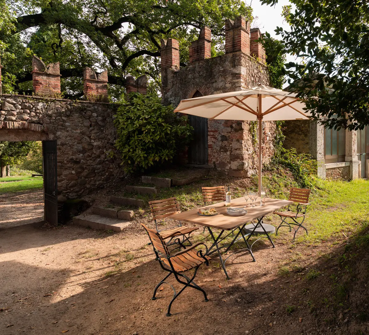 Weishäupl Klassiker Schirm Ø 350 cm in Natur über einer Gartensitzgruppe mit Holztisch und Stühlen