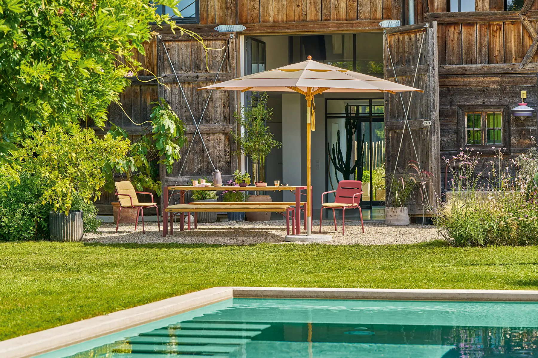 Weishäupl Teakschirm Ø 300 cm über einem Esstisch im Garten mit Pool und hochwertiger Outdoor-Einrichtung
