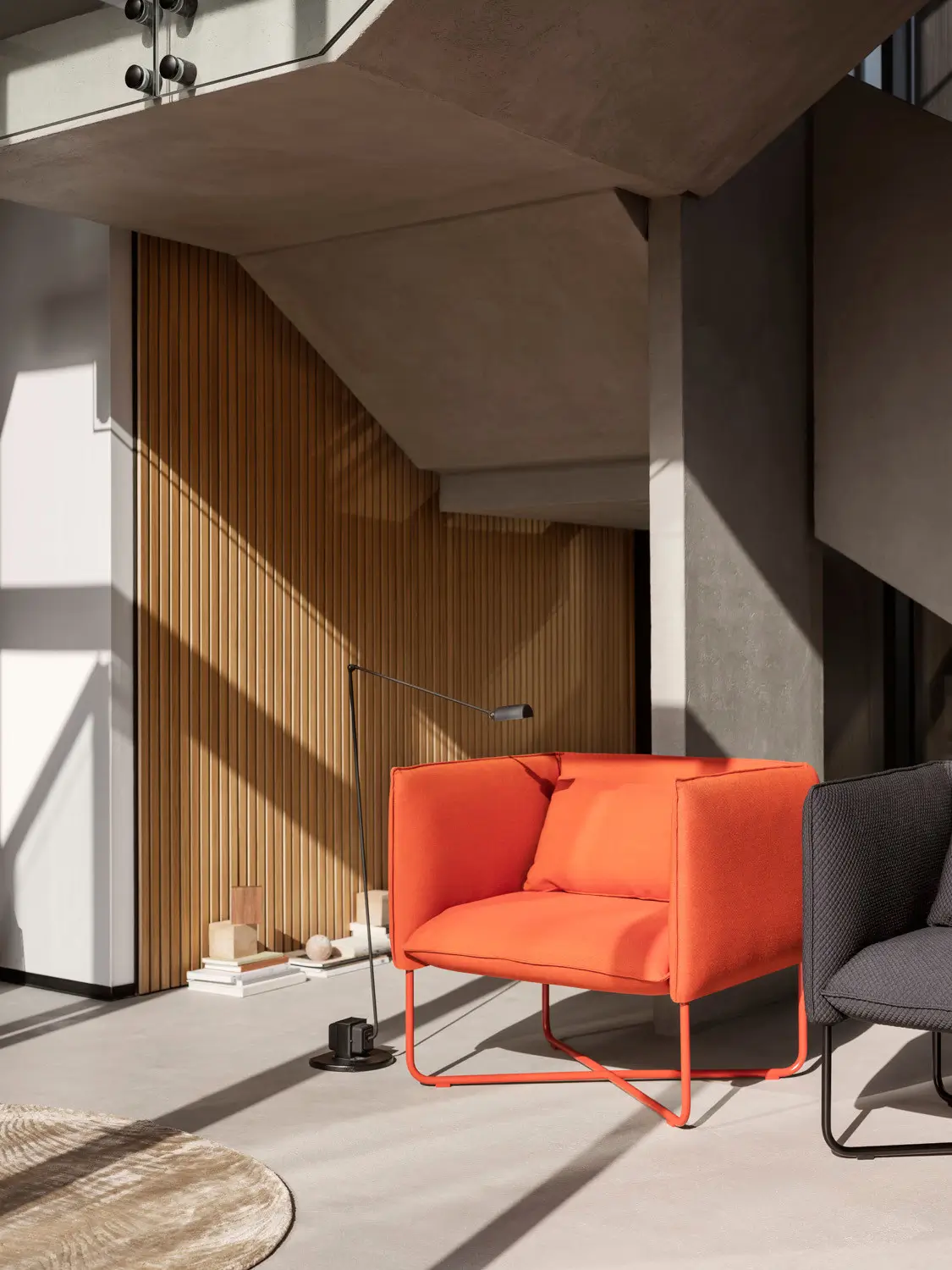 Softline Groove Sessel in Orange in einem modernen Wohnambiente mit großen Fensterflächen, Holzlamellenwand und Stehleuchte.