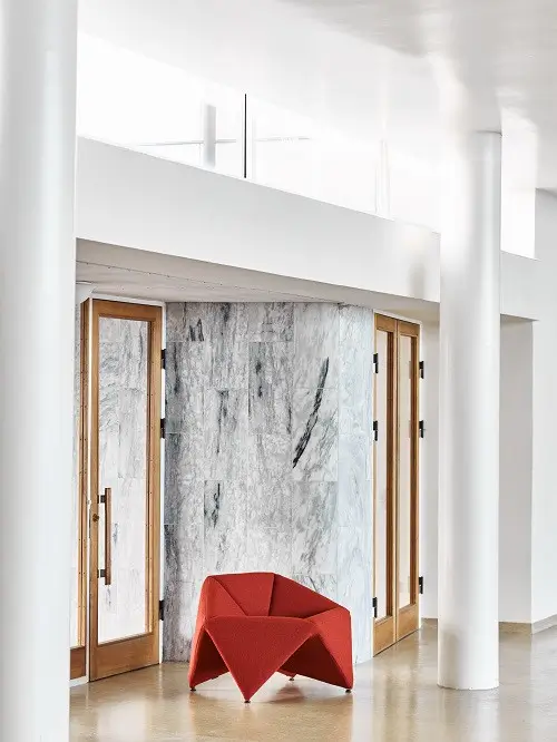 Softline Fold Sessel in Rot als markanter Akzent in einem hellen modernen Wohnambiente mit Marmorelementen, Holztüren und weißen Säulen.