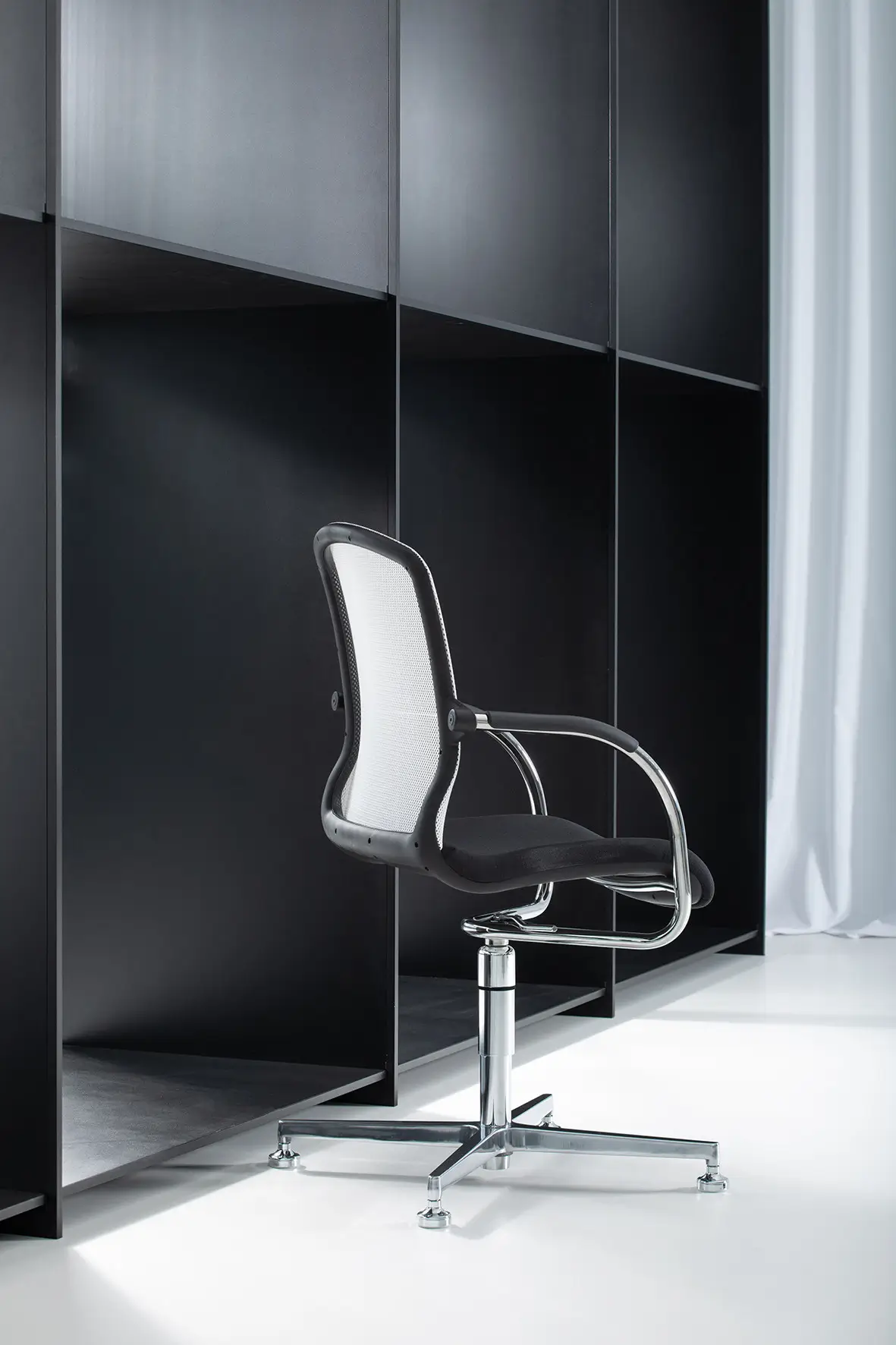 Seitenansicht des Wagner AluMedic 50 3D Visit Besucherstuhls mit verchromtem 4-Strahl-Gestell und ergonomischer Netzrückenlehne im modernen Büro.